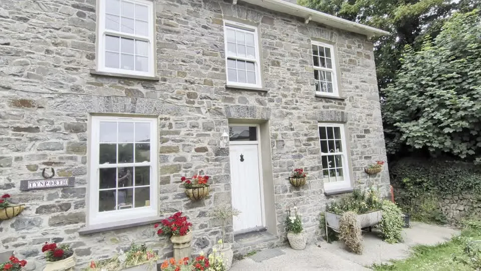 White sash-style windows fitted to a stone farmhouse in Aberaeron